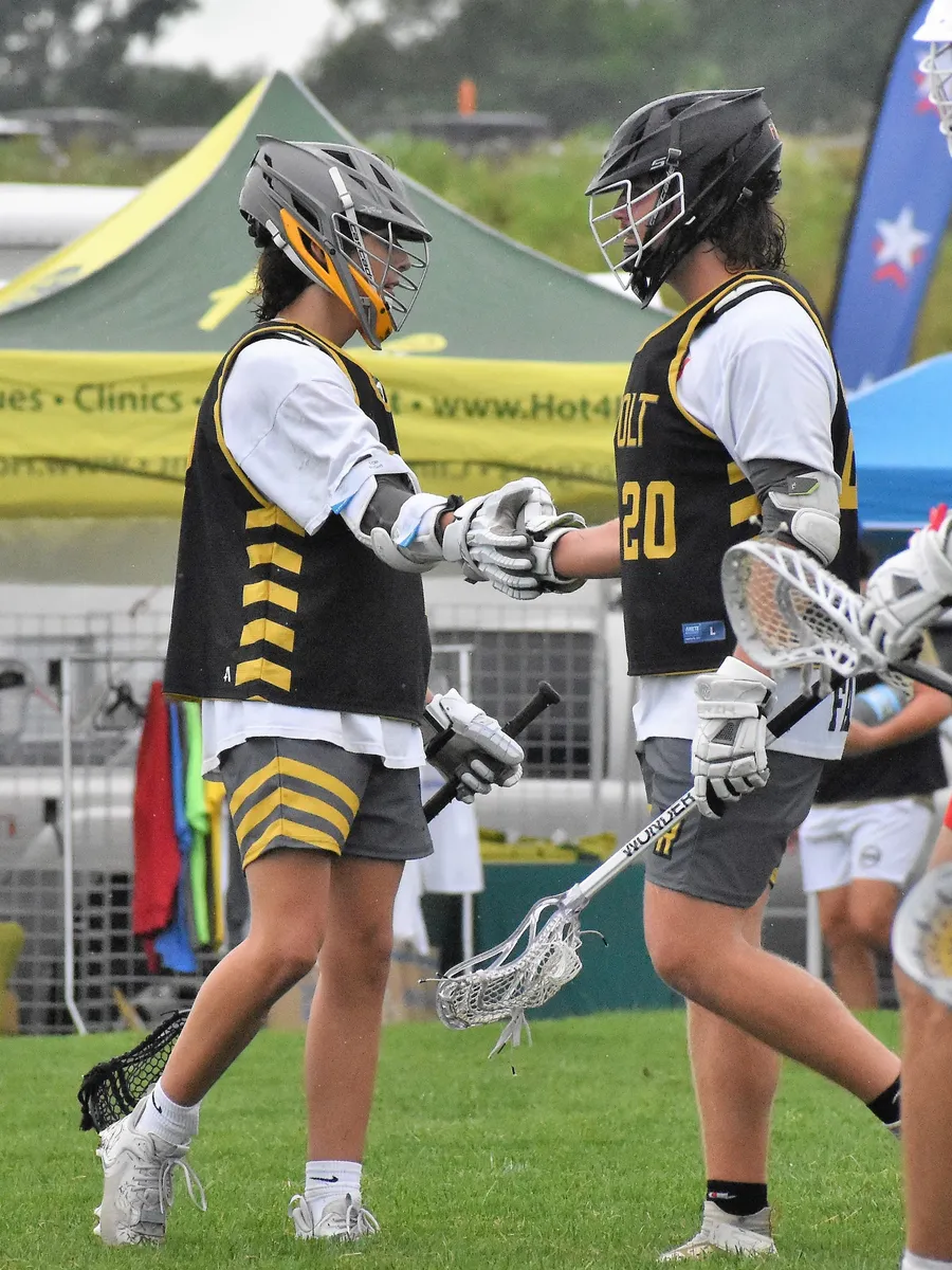 Two Revolt LC players in black and gold pinnies tapping gloves on the field after a goal